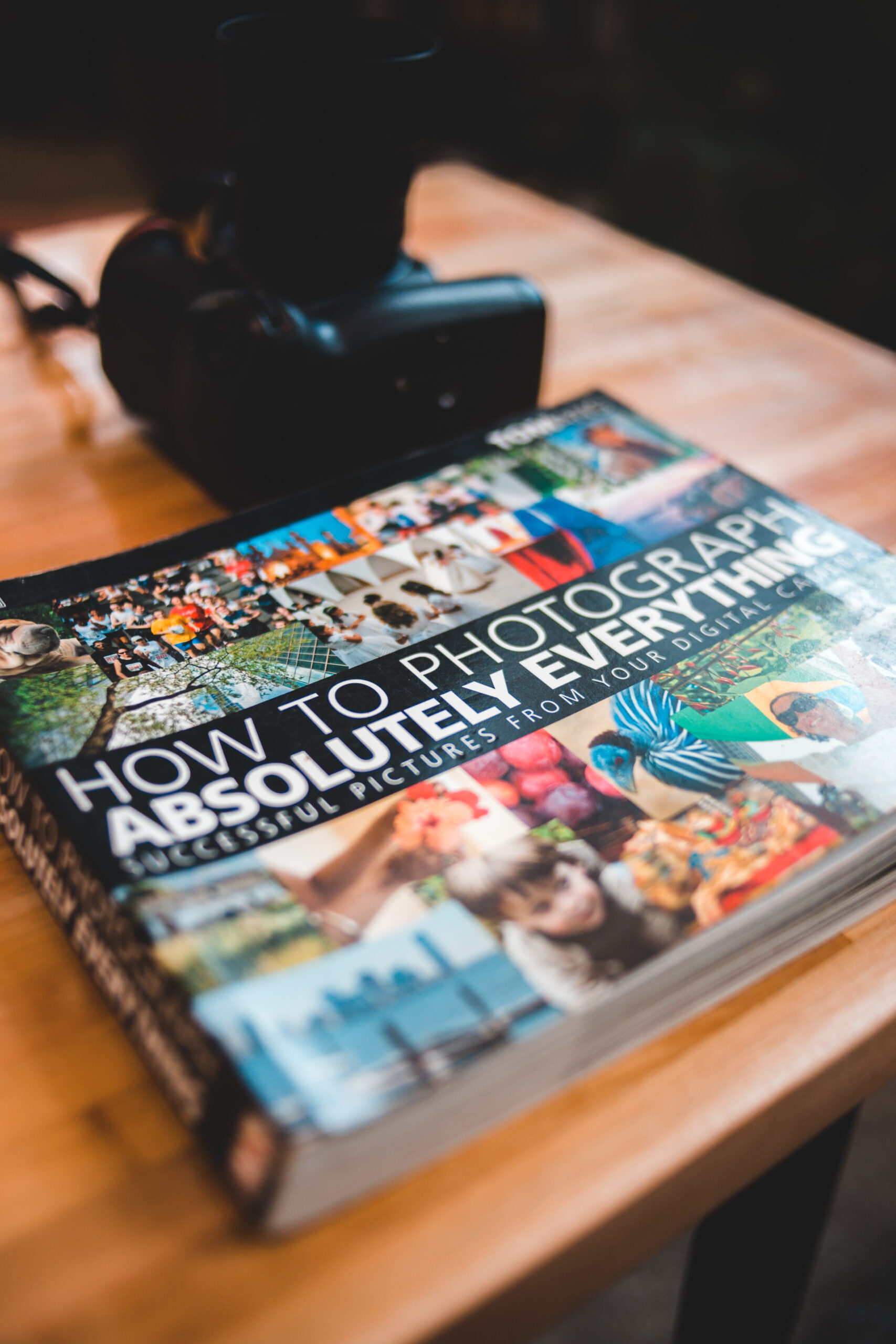 Colorful book with pictures near photo camera on table