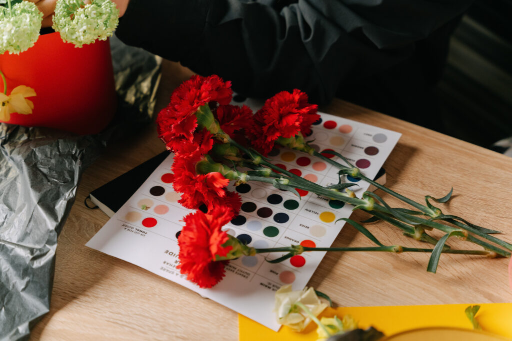 Red carnation flowers and color samples printed on paper